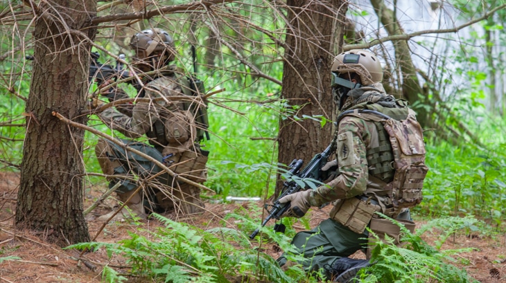 Men in camo camouflage airsoft guns war games.