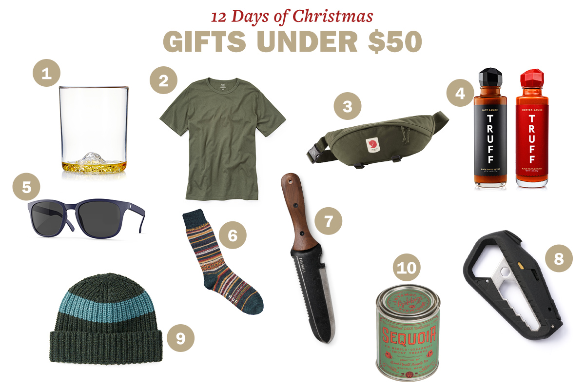 A collage of 12 Christmas gifts under $50: whiskey glass, olive green t-shirt, waist bag, truffle hot sauce, sunglasses, striped socks, garden trowel, hat, camping utensil, and a can of preserves.