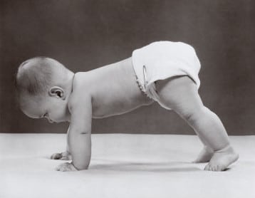 babypushups Vintage baby in diaper on hands and feet crawling.
