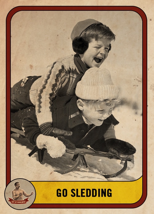 Vintage boys sledding down a hill on a toboggan.