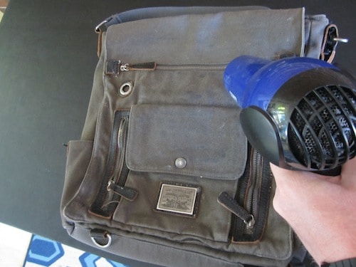 Man applying heat dryer on bag.