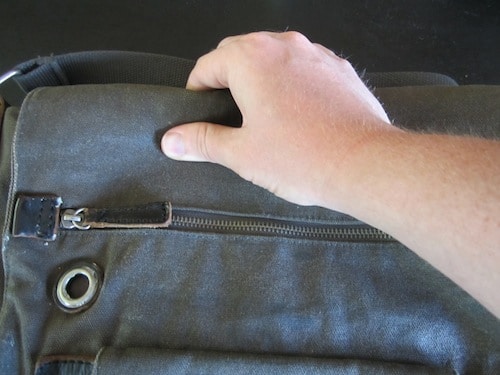 Man rubbing wax across the surface of bag.