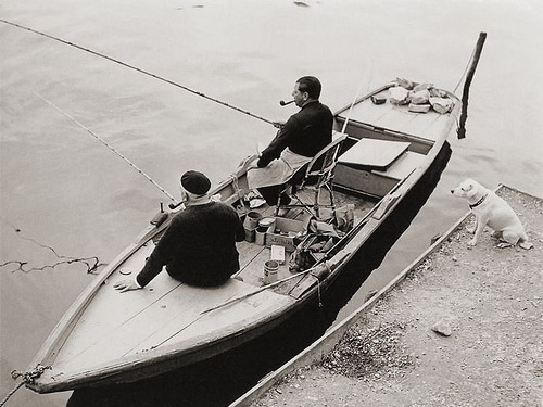 men Vintage men in fishing boat smoking pipes near dock.