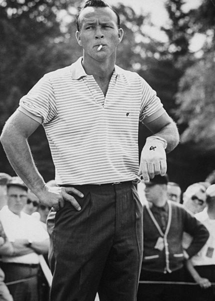 Vintage arnold palmer smoking cigarette wearing polo on golf course with a glove on left hand.
