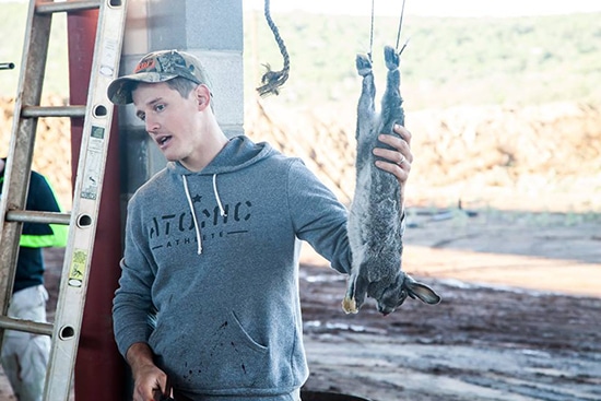 Man field dress butcher Rabbit Strung up.