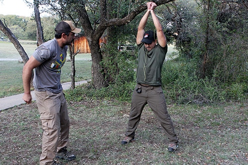 Man teaching chicken wing techniques to fellow soldier to escape from zip ties.