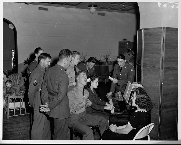 A vantage boy is singing a song and another is playing piano.