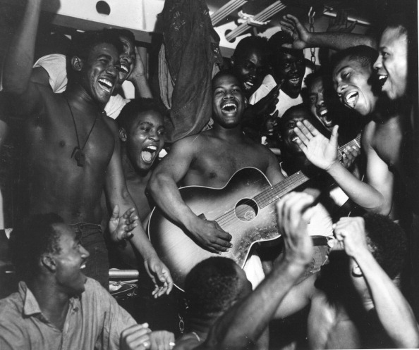 Vantage Niger playing guitar and others are singing and laughing.