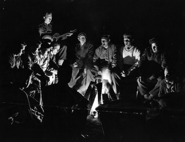 Vintage men singing around a campfire.