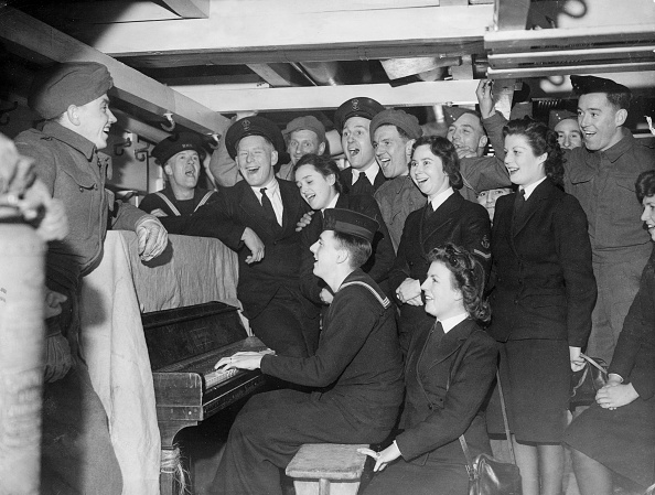 A group of vintage singing and a guy paying piano.