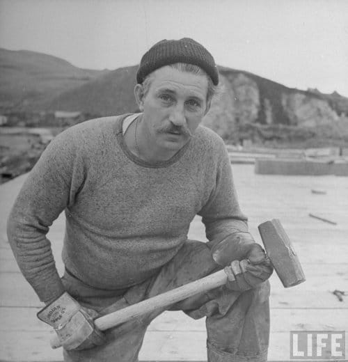 Vintage man with sledgehammer wearing stocking watch cap.