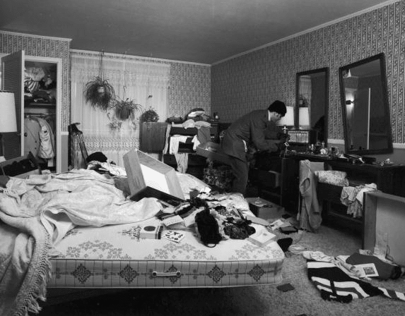 Vintage burglar rifling through bedroom contents.