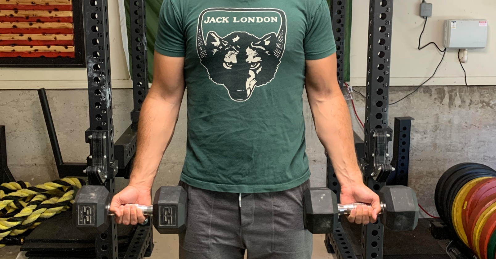 A man at the gym, performing bicep curls with dumbbells.