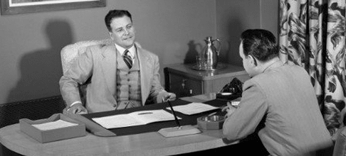 Two men conducting a job interview at a desk.