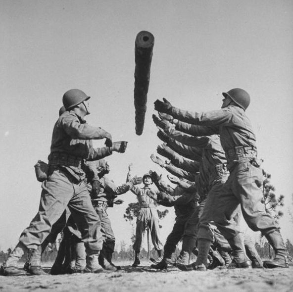 A group of soldiers are holding a large object during WWII.