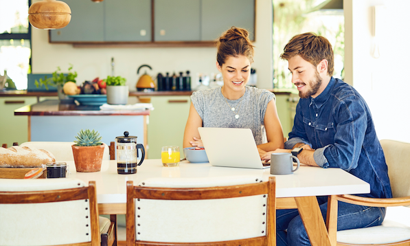A man and woman sitting at a table using a laptop during a marriage meeting.