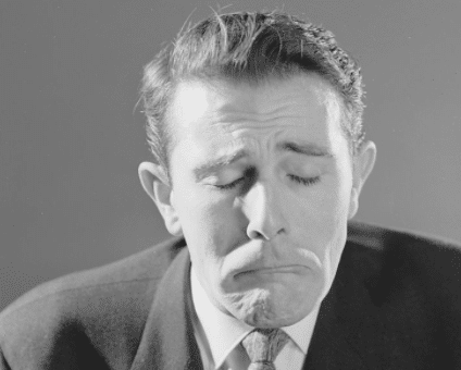 A black and white photo of a man with his eyes closed exuding an aura of negativity.